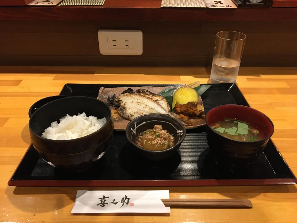 A plate and three bowls of different foods laid out on a larger black plate with chopsticks in front of it.