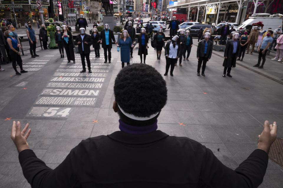 Allen Rene Louis conducts "We Will Be Back," Friday, March 12, 2021, in New York's Times Square. The "We Will Be Back" program commemorates the lost year on Broadway and attempts to shine some hope on the year to come. (AP Photo/Mark Lennihan)