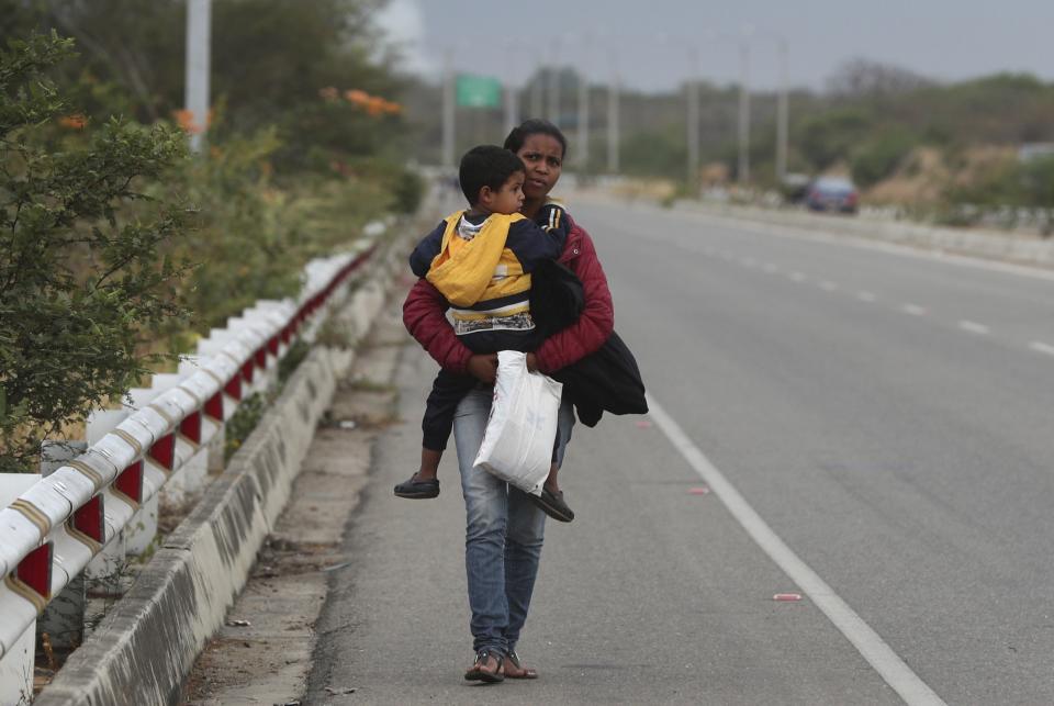 Venezuelan migrant Mary Ortega carries her son as she walks on the Pan-American Highway, after crossing the border Peru - Ecuador border, in Tumbes, Peru, Friday, June 14, 2019. Venezuelan citizens are rushing to enter Peru before the implementation of new entry requirements on migrants fleeing the crisis-wracked South American nation. (AP Photo/Martin Mejia)