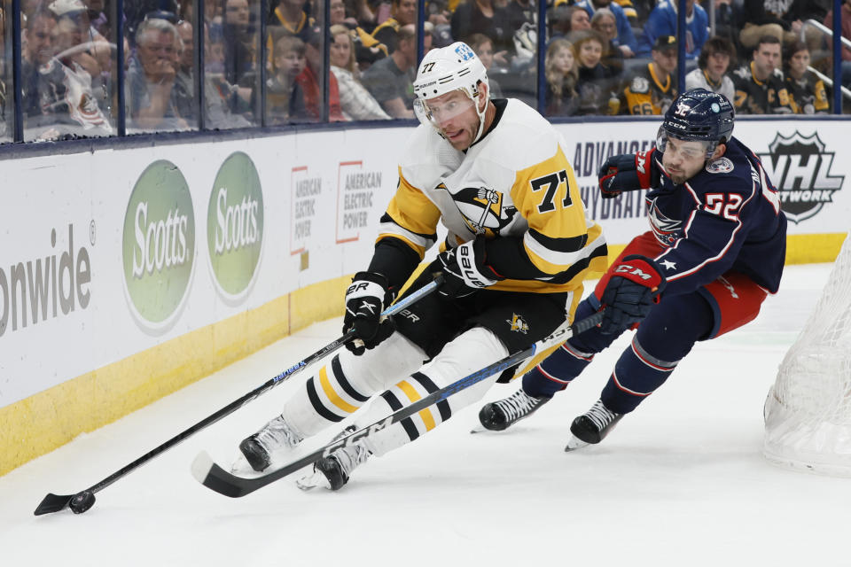 Pittsburgh Penguins' Jeff Carter, left, carries the puck behind the net as Columbus Blue Jackets' Emil Bemstrom defends during the third period of an NHL hockey game Thursday, April 13, 2023, in Columbus, Ohio. (AP Photo/Jay LaPrete)