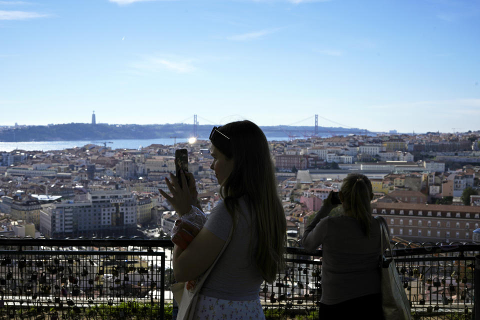 FILE - Tourists take pictures from the Nossa Senhora do Monte, or Our Lady of the Hill, viewpoint overlooking the Tagus river and downtown Lisbon in warm sunny weather, Feb. 20, 2024. Earth has exceeded global heat records in February, according to the European Union climate agency Copernicus. (AP Photo/Armando Franca, File)