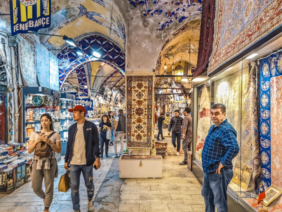 Istanbul, Turkey - October 28, 2019: Peeling paint on the walls of the pavilion of the Grand Bazaar market in Istanbul. Vintage interior of famous historical tourist place. A seller sells Turkish carpets, and tourists walk between the shopping arcades