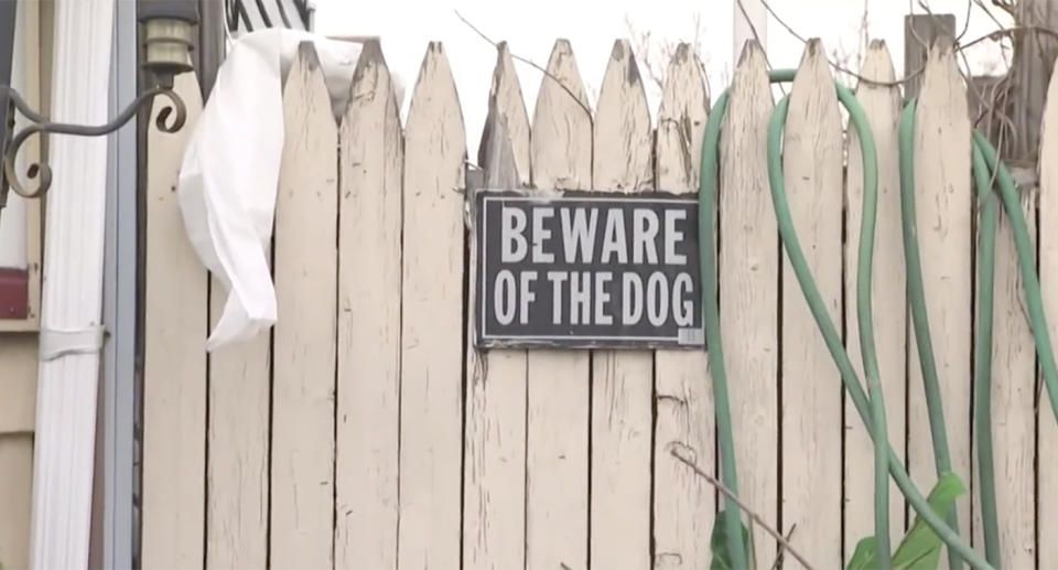 A 'Beware of the dog' sign hangs on a fence.