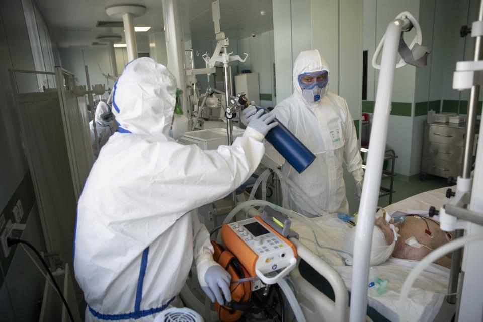 In this photo taken on Friday, May 15, 2020, Dr. Osman Osmanov, center, and Dr. Vitaly Mushkin, right, prepare a coronavirus patient on artificial lung respiration for computer tomography screening at an intensive care unit of the Filatov City Clinical Hospital in Moscow, Russia. Moscow accounts for about half of all of Russia's coronavirus cases, a deluge that strains the city's hospitals and has forced Osmanov to to work every day for the past two months, sometimes for 24 hours in a row. (AP Photo/Pavel Golovkin)