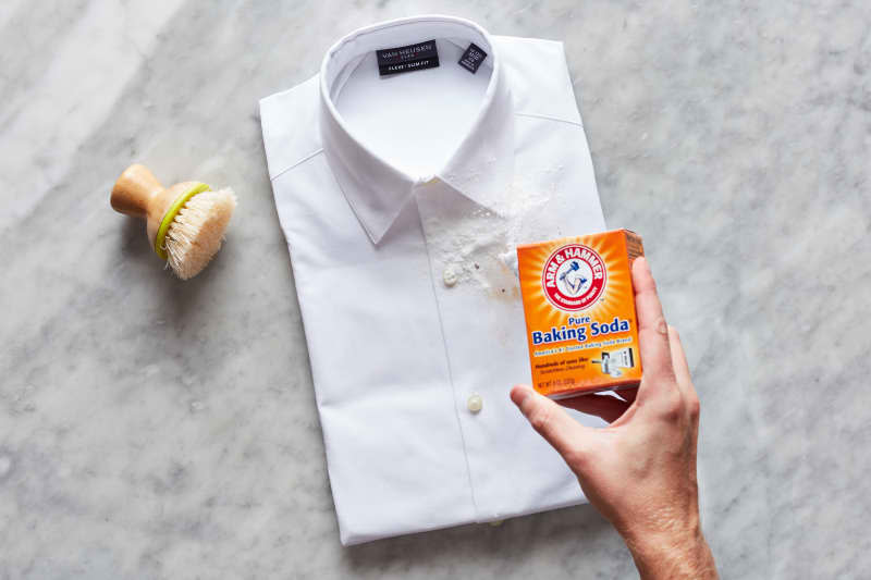 Hand pouring baking soda on shirt.