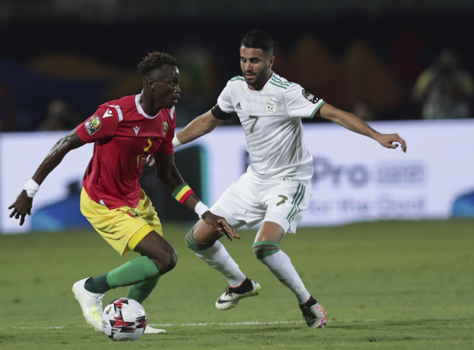 Guinea's Ernest Seka in action in front of Algeria's Riyad Mahrez during the African Cup of Nations round of 16 soccer match between Algeria and Guinea in 30 June stadium in Cairo, Egypt, Sunday, July 7, 2019. (AP Photo/Hassan Ammar)