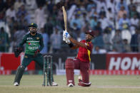 West Indies Nicholas Pooran, right, follows the ball after playing a shot for six runs while Pakistan's Mohammad Rizwan watches during the first one day international cricket match between Pakistan and West Indies at the Multan Cricket Stadium, in Multan, Pakistan, Wednesday, June 8, 2022. (AP Photo/Anjum Naveed)