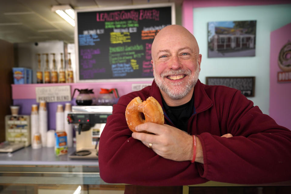 Owner Sean Young poses at Leavitt's Country Bakery, Thursday, April 13, 2023, in Conway, N.H. Young is in a federal lawsuit against the town, alleging Conway is violating his First Amendment right to keep a mural depicting various pastries above the bakery. (AP Photo/Robert F. Bukaty)