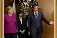 German Chancellor Angela Merkel, left, and Japanese Prime Minister Shinzo Abe, right, enter the room to observe honor guards ahead of a meeting at Abe's official residence in Tokyo Monday, Feb. 4, 2019. (Toshifumi Kitamura/Pool Photo via AP)