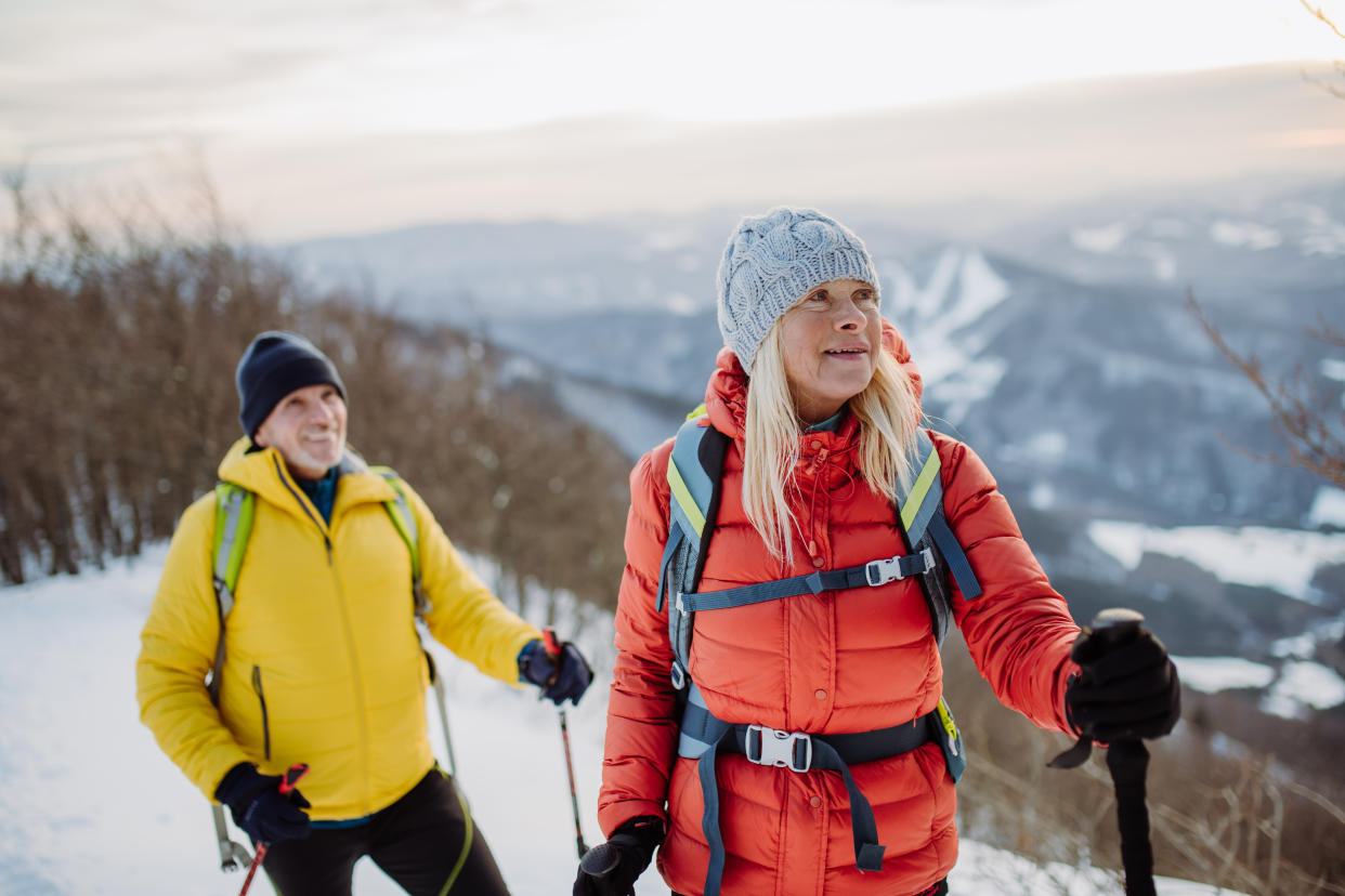 Senior couple hiking in winter mountains in beautiful sunny day winter jacket concept.