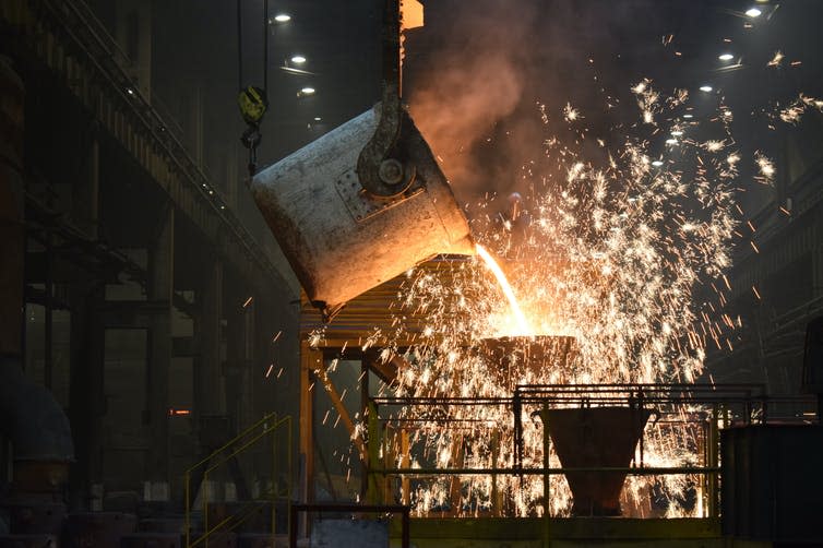 A vat of molten metal pouring onto a surface in a steelworks.