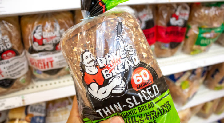 A hand holds a bag of Dave's Killer Bread at the grocery store