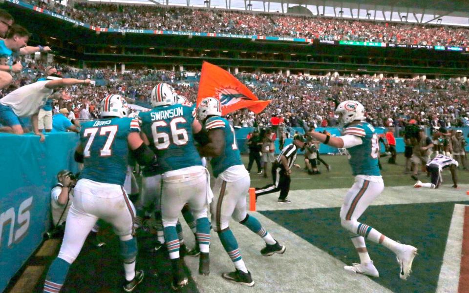 Dolphins players mob Kenyan Drake after his game-winning touchdown against the patriots - Miami Herald