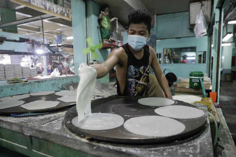 Mark Fulgencio cooks spring roll wrappers at a market in Quezon city, Philippines, Saturday Sept. 26, 2020. Government orders people in public areas to wear face masks to help curb the spread of the coronavirus. (AP Photo/Aaron Favila)