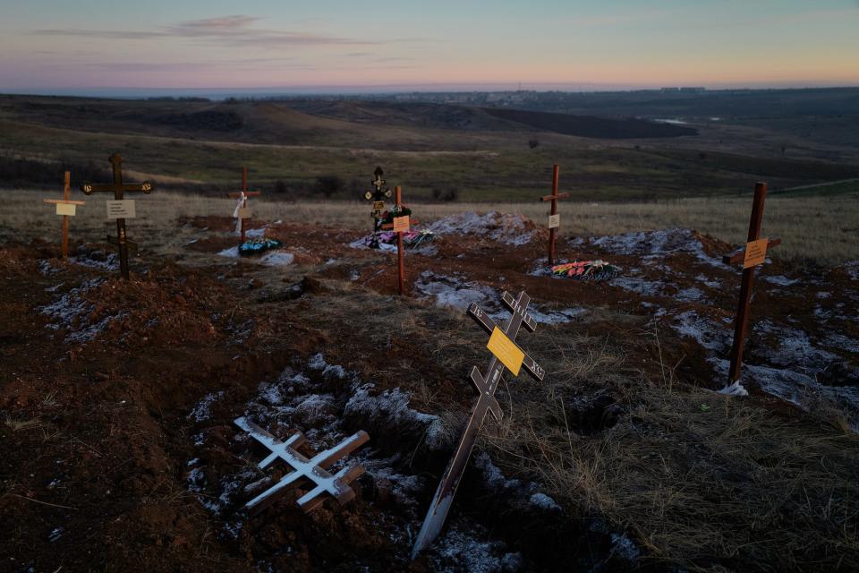 Graves are seen in a cemetery on a hill