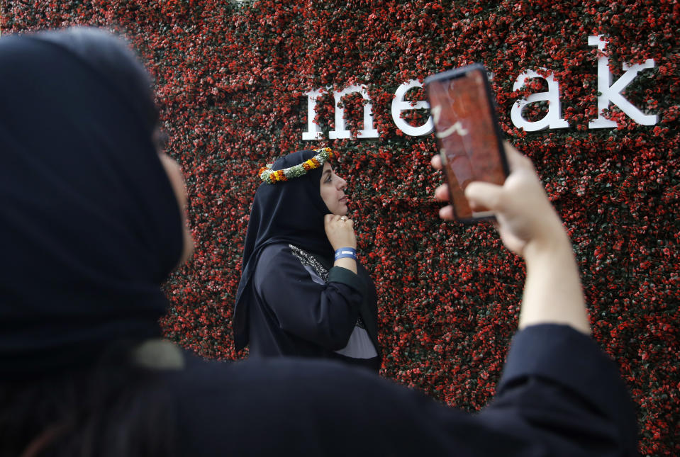 In this Thursday, Aug. 22, 2019 photo, a Saudi woman poses for a picture as she wears a colorful flower crown native to the region during the al-Soudah festival in Abha, southwest Saudi Arabia. The al-Soudah festival, which ran throughout the month of August, gave visitors a chance to experience a unique region in Saudi Arabia and take part in outdoor sports like hiking, mountain cycling, paragliding, horseback riding, zip lining and bungee jumping. (AP Photo/Amr Nabil)