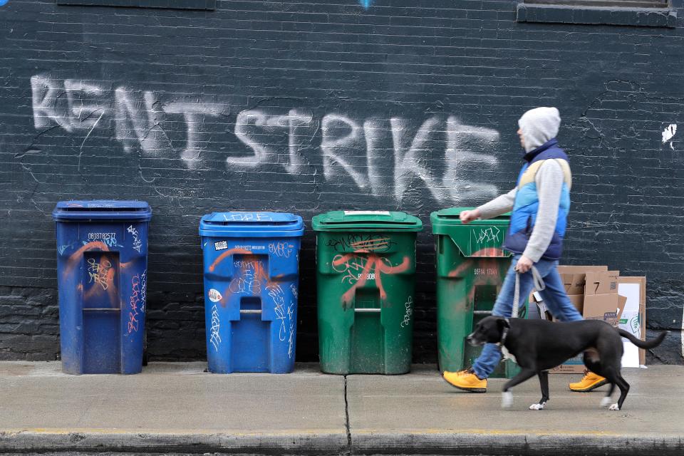 A pedestrian walks past graffiti that reads "Rent Strike" Wednesday, April 1, 2020, in Seattle's Capitol Hill neighborhood. With millions of people suddenly out of work, some tenants in the U.S. are vowing to go on a rent strike until the new coronavirus pandemic subsides.