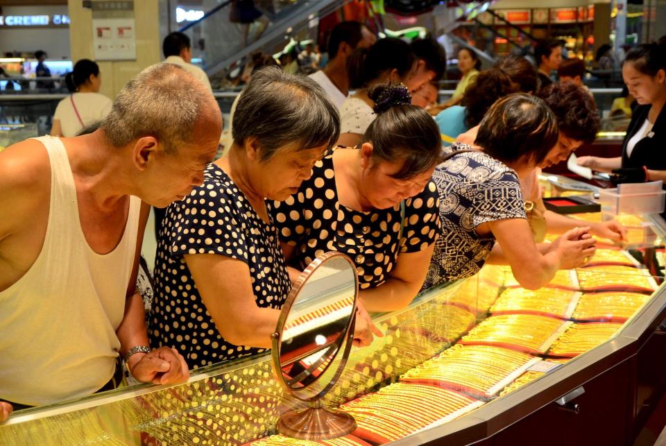 Customers looking at glass cases of gold necklaces.