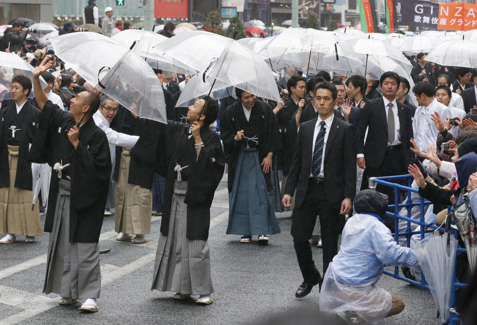 Kabuki actor Ebizo Ichikawa, left, Ennosuke Ichikawa, center, and other actors parade at Ginza shopping district in Tokyo, Wednesday, March 27, 2013. Some 60 actors paraded in the rain Wednesday to newly renovated Tokyo theatre ahead of its official opening. (AP Photo/Shizuo Kambayashi)