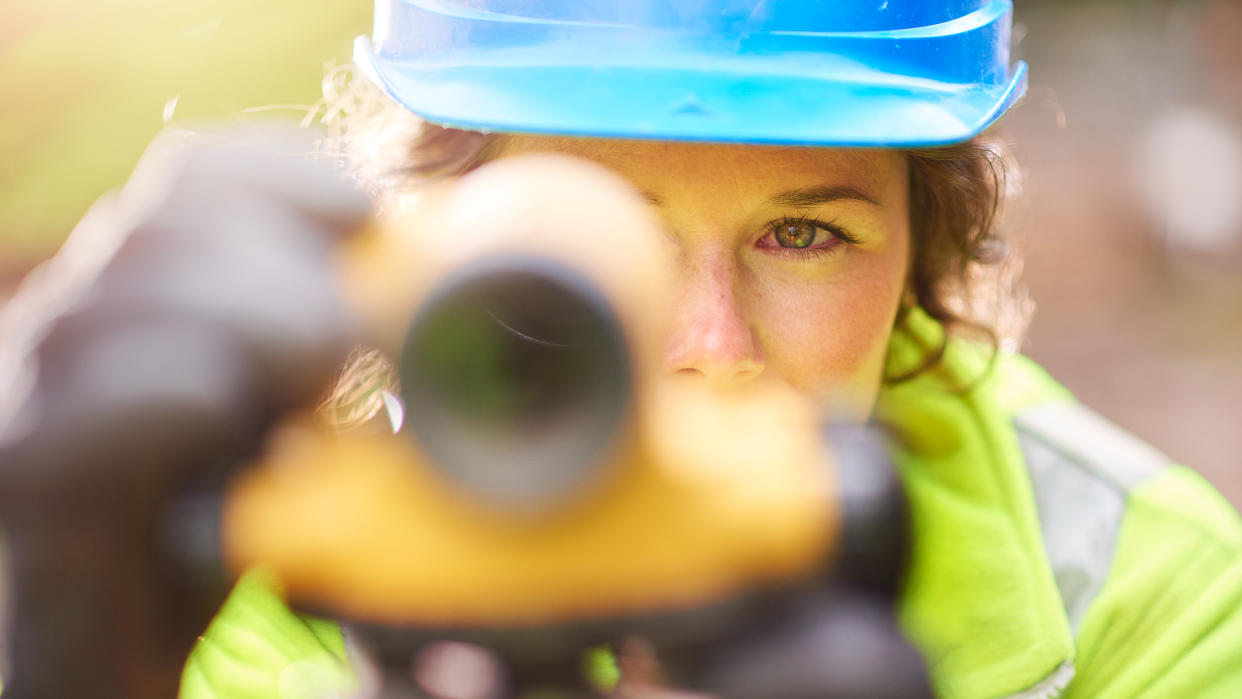 a young female surveyor checking her levels on site.