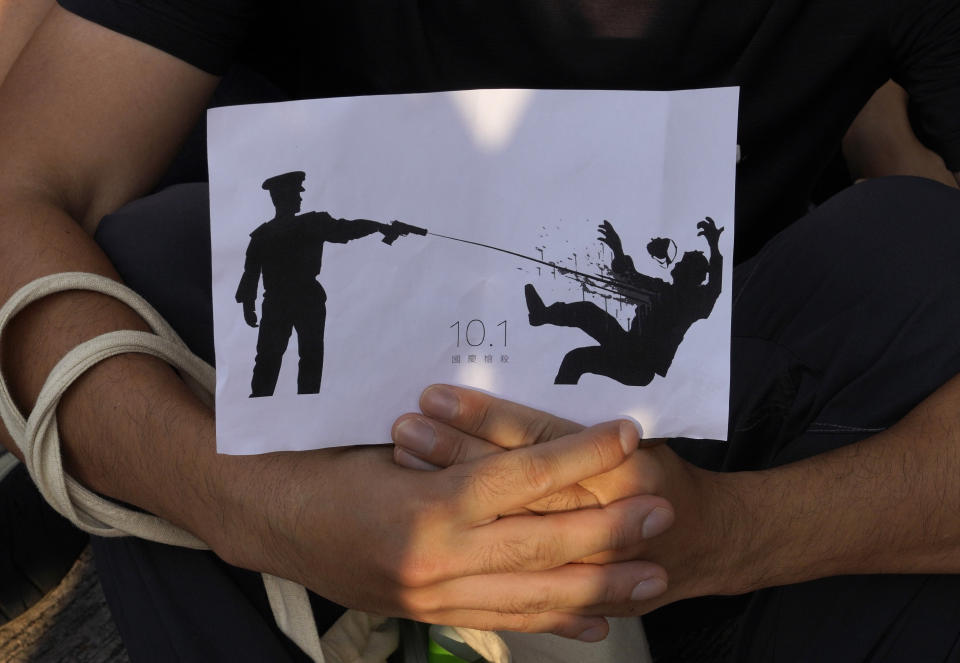 A supporter holds a printing featuring a protester being shot in the chest by police during a strike in Hong Kong, Wednesday, Oct. 2, 2019. Hundreds of students at a Hong Kong college have staged a strike to condemn police shooting of a teenager during widespread violence in the semi-autonomous Chinese territory at pre-democracy protests that marred China's National Day. (AP Photo/Vincent Yu)