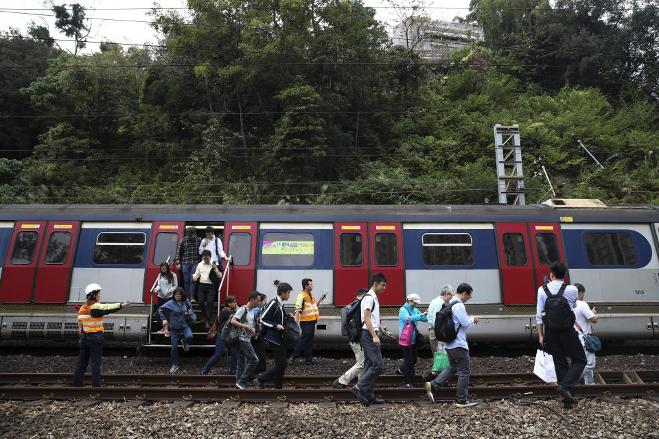 Commuters disembark the train and walk on the railway after the train service is disrupted by pro-democracy protesters in Hong Kong, Tuesday, Nov. 12, 2019. Protesters disrupted the morning commute in Hong Kong on Tuesday after an especially violent day in the Chinese city that has been wracked by anti-government protests for more than five months. (AP Photo)