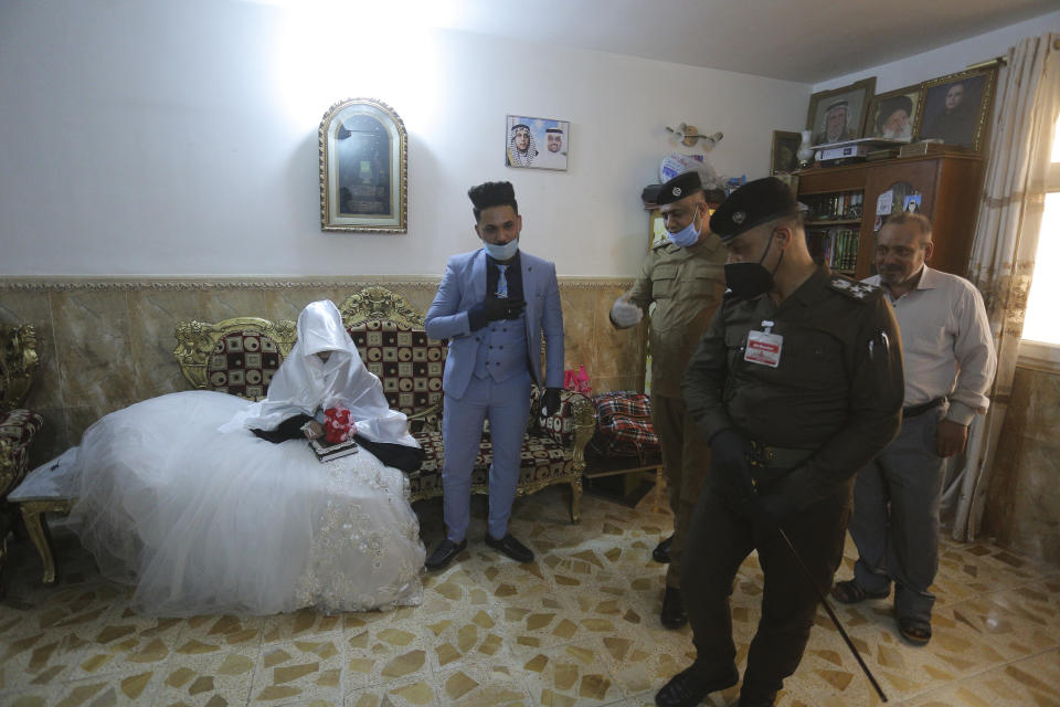 In this Thursday, April 9, 2020 photo, police officers arrive to escort Ahmed Khaled al-Kaabi and his bride Ruqaya Rahim during their wedding in Najaf, Iraq, hardest hit town by coronavirus in the country with government banned large public gatherings. Unwilling to postpone the wedding, al-Kaabi asked the local security forces to help him wed his beloved. The police responded by providing the groom vehicles blasting music to bring his bride to the family home for a small celebration of just six people. (AP Photo/Anmar Khalil)