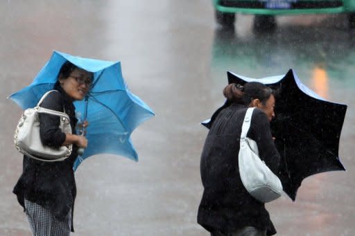 People walk in the heavy rain and wind brought by typhoon Bolaven in Jilin, northeast China's Jilin province, on Thursday. Scientists say worse droughts, floods and storms are consistent with models that link disruption to Earth's climate system with heat-trapping fossil-fuel emissions