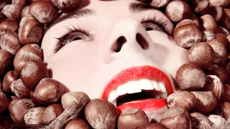 woman's face drowning in hazelnuts