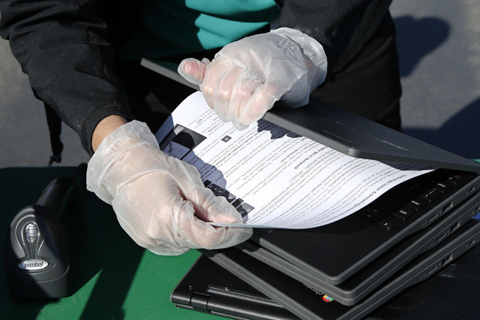 Lindsey Lilley, an employee of the Elk Grove Unified School District, places start up instructions into a Chromebook to be assigned to a student in the district, at Monterey Trail High School in Elk Grove, Calif., Thursday, April 2, 2020. In response to the order to close school buildings to the public due to the coronavirus, the laptops are being loaned to qualifying district families as part of the district's "distance learning" program which will be ready to go live by mid-April. (AP Photo/Rich Pedroncelli)