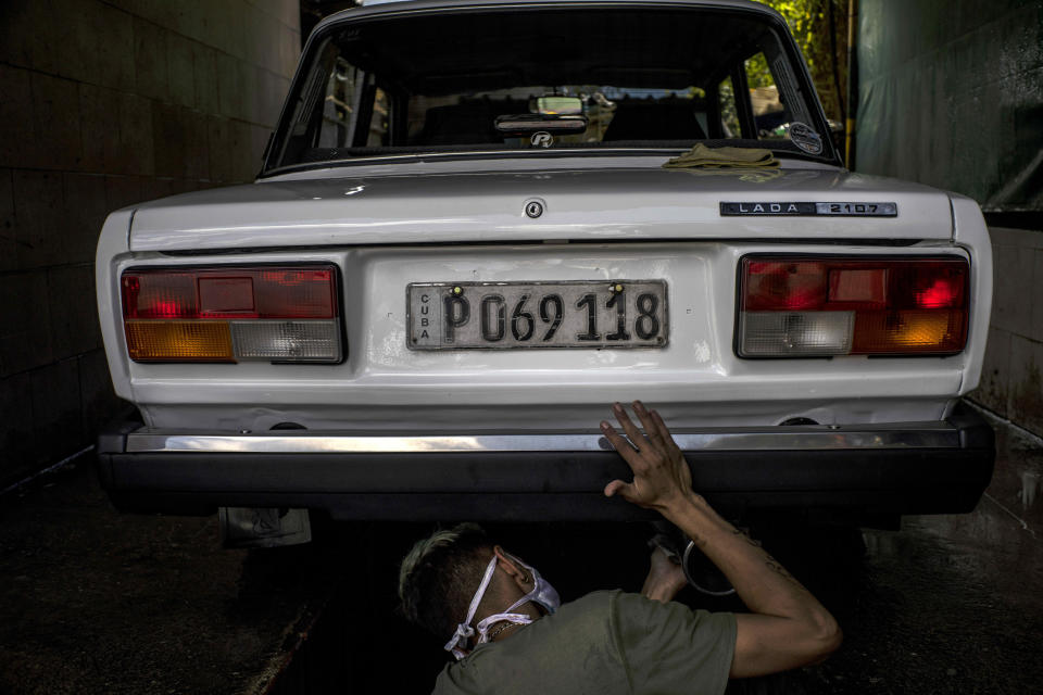 A worker cleans a Soviet-era Lada car during the Lada Cuba Club meeting in Havana, Cuba, Sunday, March 21, 2021. With the collapse of the Soviet Union and the ongoing U.S. economic embargo making it difficult to procure spare parts, Lada drivers adapt new parts to keep their cars rolling, while others strive to leave them just as they were off the assembly line. (AP Photo/Ramon Espinosa)