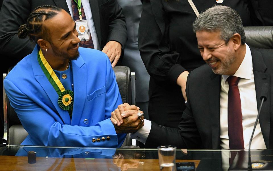 British F1 driver Lewis Hamilton (L) shakes hands with Brazil's Lower House President Arthur Lira after being awarded the Honorary Brazilian Citizenship, during a ceremony at the National Congress, in Brasilia on 7 November 2022. - EVARISTO SA/AFP via Getty Images