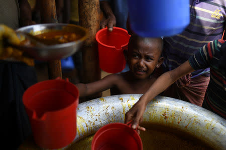 A Rohingya refugee child is handed food rations at Jamtoli refugee camp near Cox's Bazaar, Bangladesh, March 29, 2018. REUTERS/Clodagh Kilcoyne