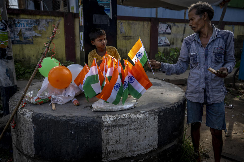 A rickshaw puller buys an Indian flag from a boy near a traffic intersection on Independence Day in Gauhati, northeastern state of Assam, India, Monday, Aug. 15, 2022. The country is marking the 75th anniversary of its independence from British rule. (AP Photo/Anupam Nath)