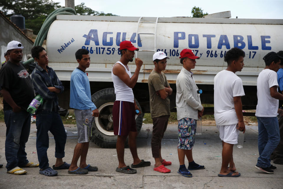 Migrants wait in line beside a water truck to brush their teeth and fill water bottles, as a caravan of Central Americans trying to reach the U.S. border halts for a rest day in San Pedro Tapanatepec, Oaxaca state, Mexico, Sunday, Oct. 28, 2018. Thousands of migrants took a break Sunday on their long journey toward the U.S. border roughly 1000 miles away, with Mexican government agencies seeming to waver between helping and hindering.(AP Photo/Rebecca Blackwell)