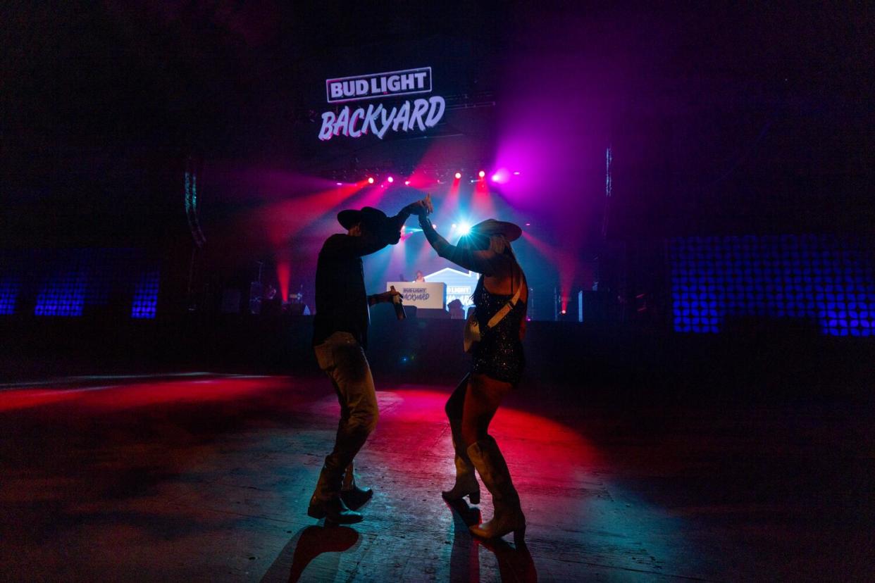 A silhouette of a couple dancing under a sign that reads Bud Light Backyard