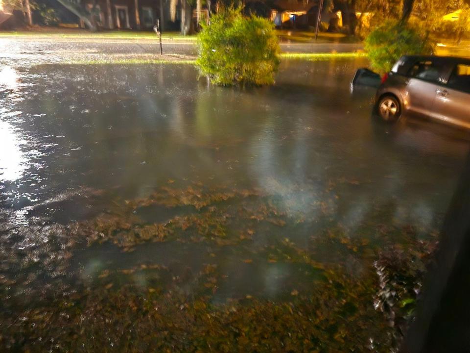 Flooding caused by heavy rains takes over Kelly Manu's driveway and front yard, submerging part of her car.