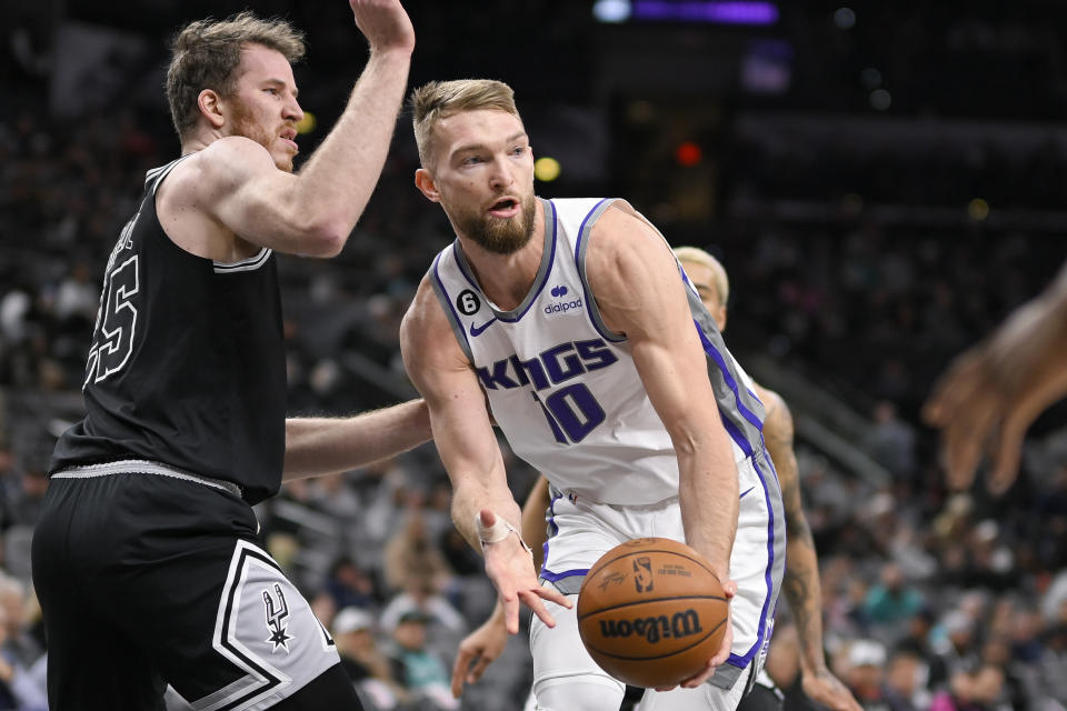 Sacramento Kings' Domantas Sabonis (10) looks to pass the ball as he is defended by San Antonio Spurs' Jakob Poeltl during the first half of an NBA basketball game, Wednesday, Feb. 1, 2023, in San Antonio. (AP Photo/Darren Abate)