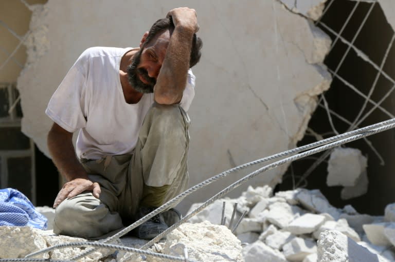 A man waits as Syrian civil defence workers look for survivors under the rubble of a collapsed building following reported air strikes on July 17, 2016 in Aleppo