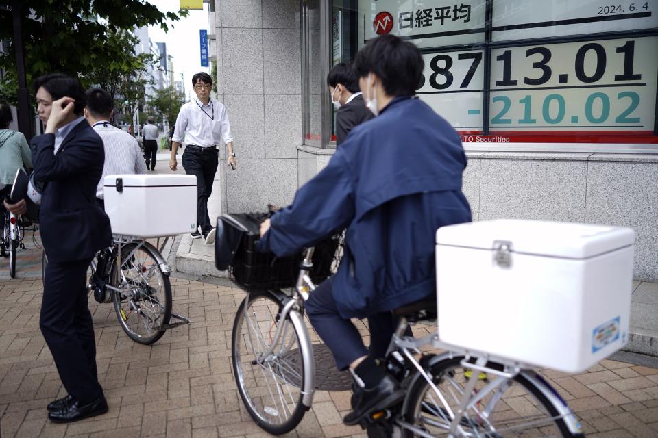 People pass in front of an electronic stock board showing Japan's Nikkei 225 index at a securities firm Tuesday, June 4, 2024, in Tokyo. (AP Photo/Eugene Hoshiko)