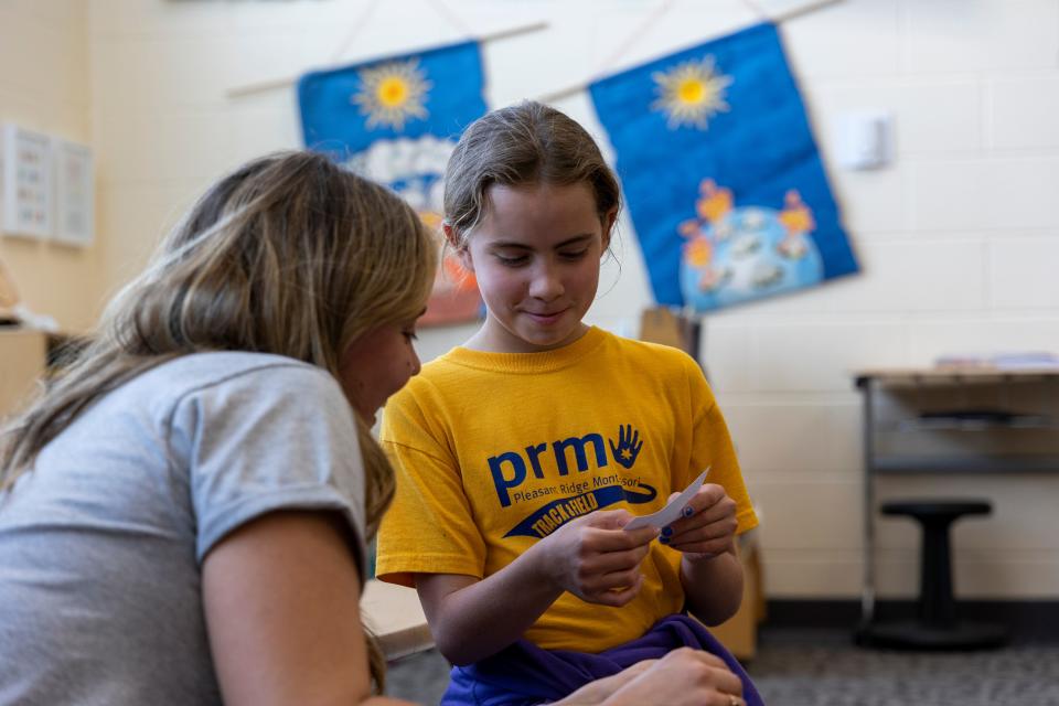 Sam Bourgeois, a third grader at Pleasant Ridge Montessori School, asks teacher Sarah Lofquist for clarification on how to pronounce a word while presenting a group science project to the class May 24.