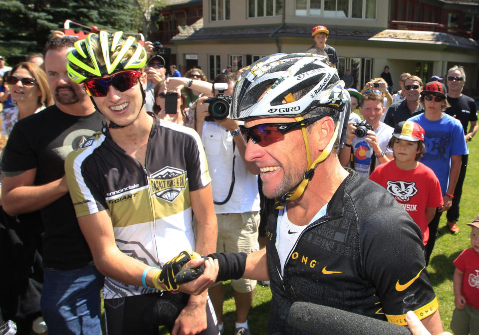 Lance Armstrong, front, talks to reporters after his second-place finish in the Power of Four mountain bicycle race at the base of Aspen Mountain in Aspen, Colo., on Saturday, Aug. 25, 2012. Race-winner Keegan Swirbul, 16, of Aspen, left, clapso his hand. 