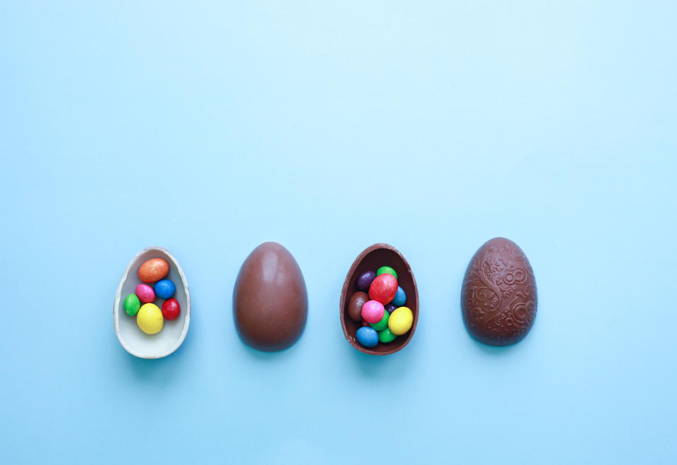 Chocolate Easter Eggs with Colorful Candies over blue background. Greeting card for holidays.
