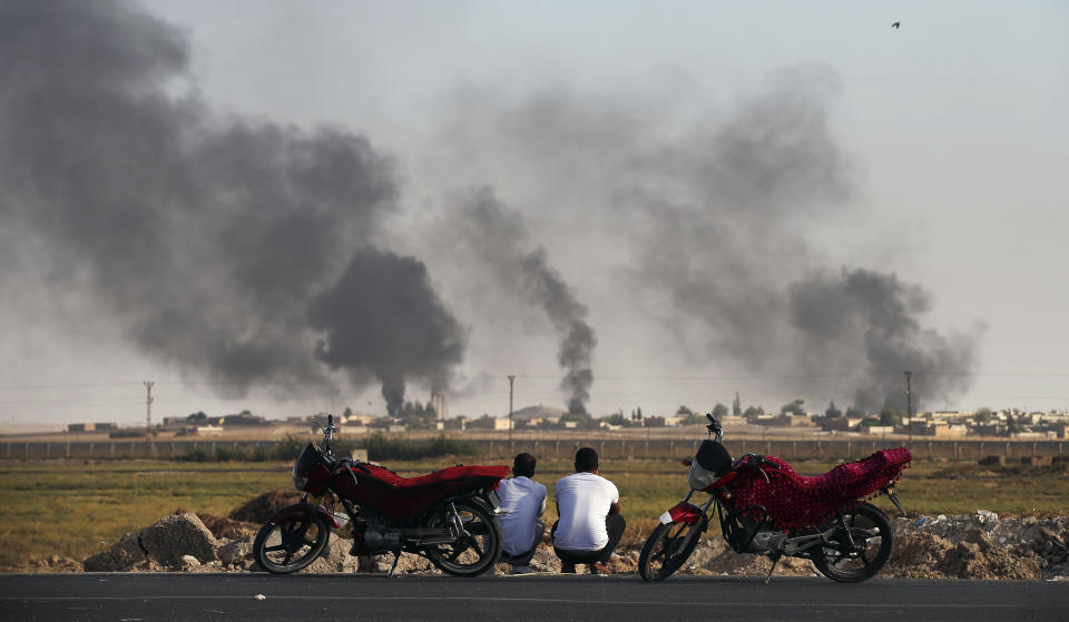 People in Akcakale Sanliurfa province, southeastern Turkey, at the border with Syria, watch smoke billowing inside Syria, during bombardment by Turkish forces, Thursday, Oct. 10, 2019. Turkey's foreign minister says Turkish troops intend to move some 30 kilometers (19 miles) deep into northern Syria and that its operation will last until all "terrorists are neutralized," a reference to Syrian Kurdish fighters. (AP Photo/Emrah Gurel)