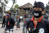 Security guards wearing face masks lineup during a briefing at the opening of Kuta beach in Bali, Indonesia, Thursday, July 9, 2020. Indonesia's resort island of Bali reopened after a three-month virus lockdown Thursday, allowing local people and stranded foreign tourists to resume public activities before foreign arrivals resume in September. (AP Photo/Firdia Lisnawati)