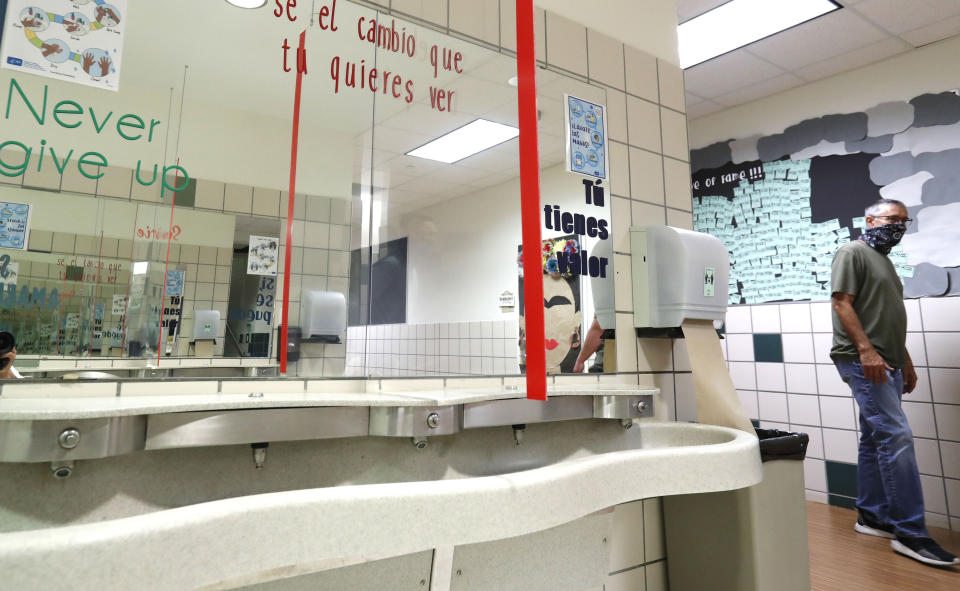 Bill Goff, Richardson Independent School District director of facility services, looks over a restroom with just installed plexiglass barriers for the sink at Bukhair Elementary School in Dallas, Wednesday, July 15, 2020. Texas Education Commissioner Mike Morath told the state Board of Education on Tuesday that the annual State of Texas Assessments of Academic Readiness, also known as STAAR, will return in the 2020-2021 school year. (AP Photo/LM Otero)