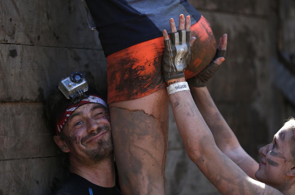 RNPS YEAR END 2014 - BEST OF SPORT ODDLY Participants climb over a wall at the "Tough Mudder" endurance event series in Arnsberg in this September 6, 2014 file photo. REUTERS/Ina Fassbender/Files (GERMANY - Tags: SOCIETY SPORT TPX IMAGES OF THE DAY)