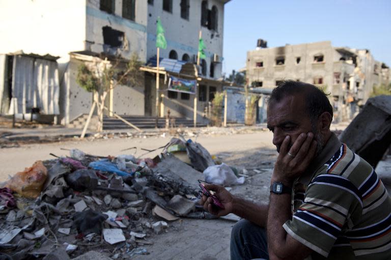 Abu Naael, a Palestinian man living with his family in his partly destroyed home in the Shejaiya neighborhood of Gaza City, listens to the radio on his mobile phone on August 18, 2014