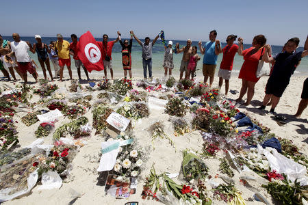 FILE PHOTO: People join hands as they observe a minute's silence in memory of those killed in an attack by an Islamist gunman, at a beach in Sousse, Tunisia July 3, 2015. REUTERS/Anis Mili/File Photo