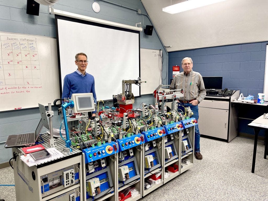 North Central Michigan College instructors Jerry Brusher (left) and Bob Carpenter stand beside the Amatrol 870 Mechatronics system, a replica of the modern smart factory, inside the college’s new Manufacturing and Engineering Technology Lab.